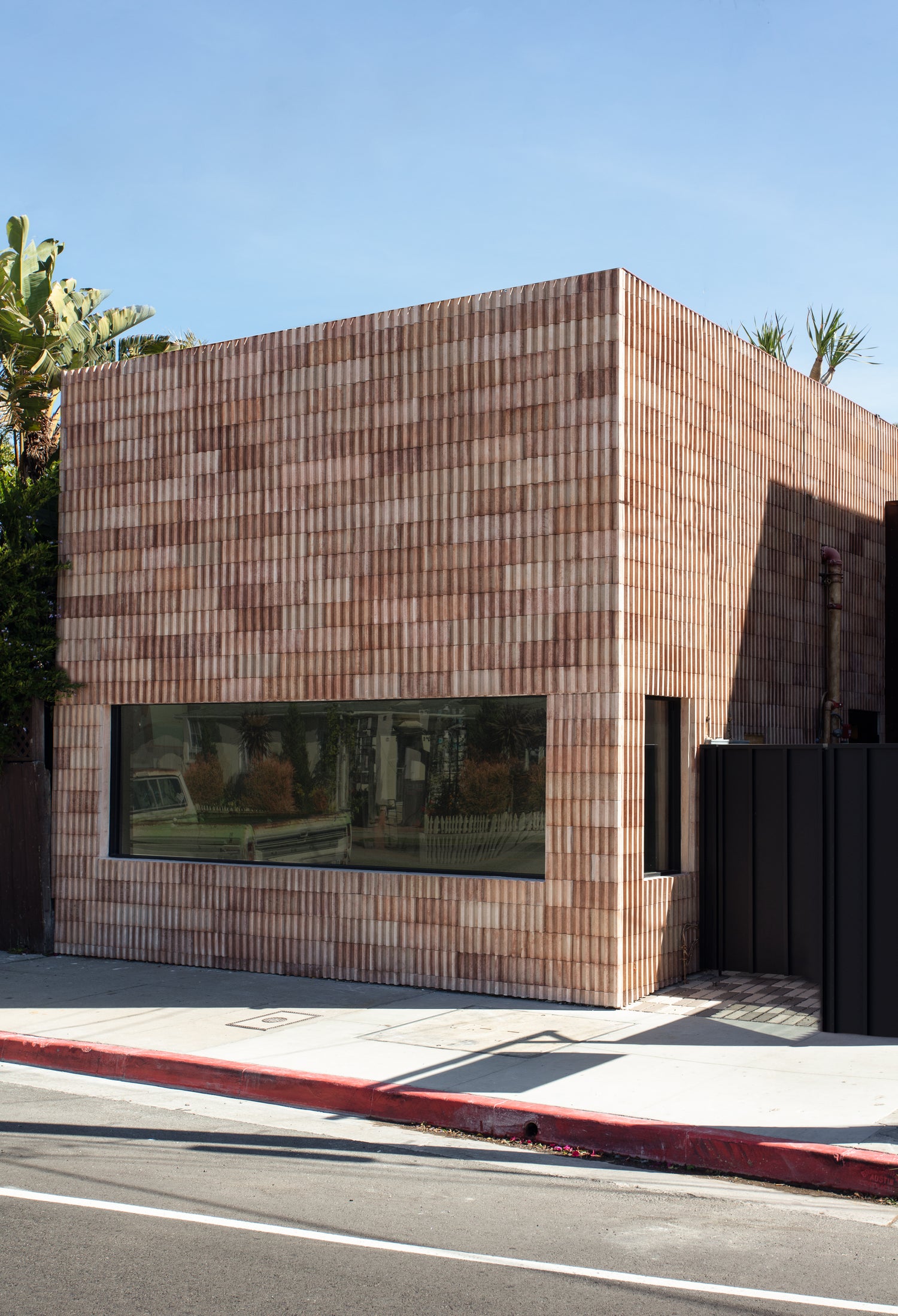 a commercial building on abbot kinney blvd in venice, ca that is clad in clay colored dimensional tiles made from concrete with a bold modern patchwork look