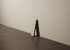 a 2"x10" bespoke fluted concrete tile with eight peaks leans against a textured, plaster wall on an unfinished concrete floor